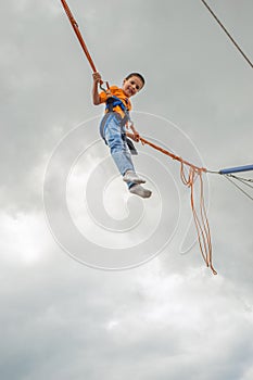 Happy young boy jumping on bungee trampoline