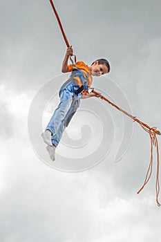 Happy young boy jumping on bungee trampoline