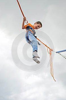 Happy young boy jumping on bungee trampoline