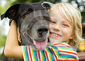 Happy young boy lovingly hugging his pet dog