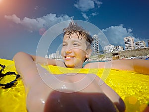 Happy young boy in the ocean on surfboard