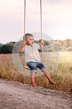 Happy young boy playing on swing in a park