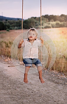 Happy young boy playing on swing in a park