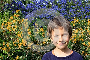 A happy young boy portrait outdoor in the spring garden. Children gardening design. Floral background