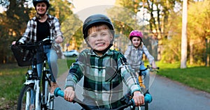 happy young boy riding a bicycle together with family