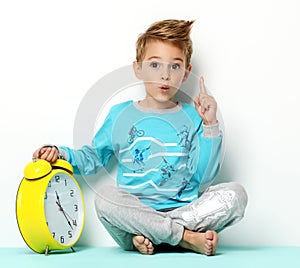 Happy young boy sitting in blue sweater thinking and looking up