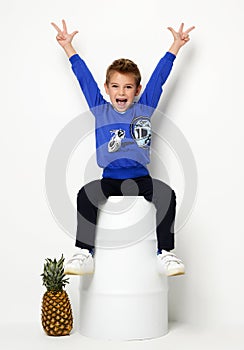 Happy young boy sitting in blue sweater thinking and looking up