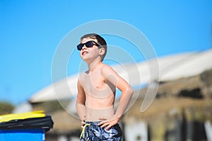 Happy young boy with sunglasses enjoys outdoor time at sea side