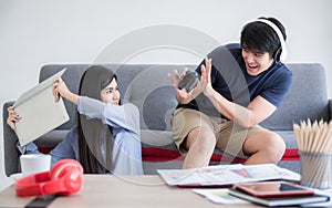 Happy young boyfriend wear headphone holding joystick playing video game with make fun and tease girlfriend to displeased and