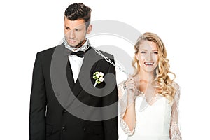 happy young bride with chain and leashed sad groom