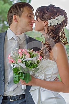 Happy young bride and groom embrace and kiss