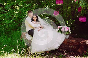 Happy young bride and groom in a pink decorated with peonies area in nature, family, relationships, romance, smiles, hugs, love