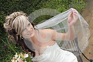 Happy young bride holding bridal veil out
