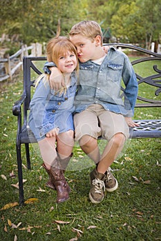 Happy Young Brother and Sister Sitting Together Outside