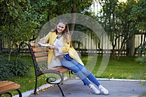 Happy young brunette sitting on a park bench