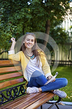 Happy young brunette sitting on a park bench