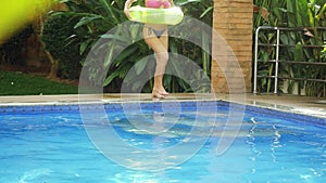 Happy young brunette woman with an inflatable circle runs into the swimming pool in slow motion. 1920x1080