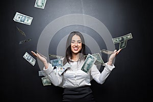 Happy young brunette woman in white shirt showing smartphone with blank screen and cash money in hands isolated on black backgroun