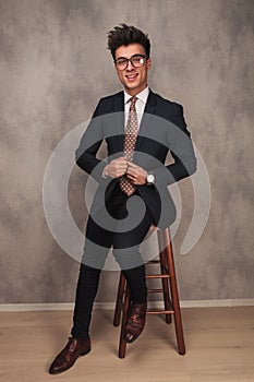 Happy young business man pulling his collar while sitting