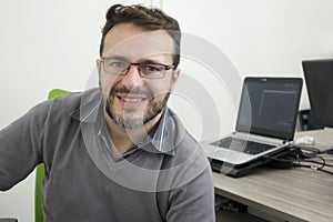 Happy young business man, software developer, computer technician working in modern office