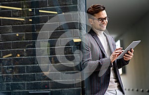 Happy young business man with tablet at work in modern urban background