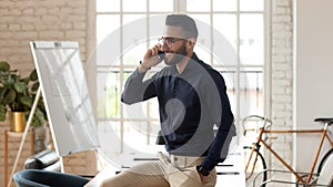 Happy young business man talking on phone in office room