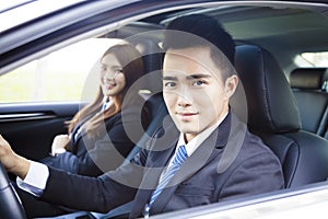 Happy young business man and woman driving in the car