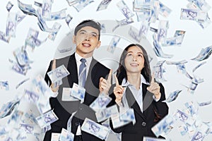 Happy young business man and woman hands pointing up and under money rain