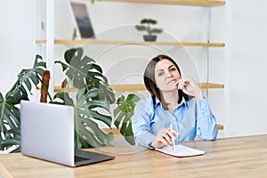 Happy young business woman entrepreneur using computer looking at screen working in internet sit at office desk