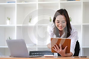 Happy young business woman entrepreneur using computer looking at screen working in internet sit at office desk, smiling