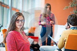 Happy young business woman with her staff, people group in background at modern bright office indoors