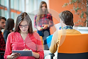 Happy young business woman with her staff, people group in background at modern bright office indoors