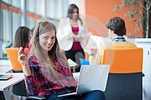 Happy young business woman with her staff, people group in background at modern bright office indoors