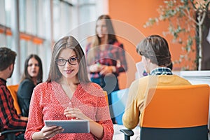 Happy young business woman with her staff, people group in background at modern bright office indoors