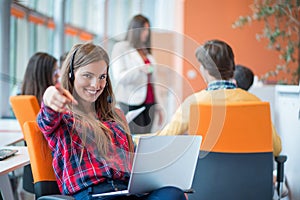 Happy young business woman with her staff, people group in background at modern bright office indoors