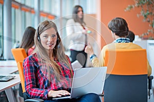 Happy young business woman with her staff, people group in background at modern bright office indoors