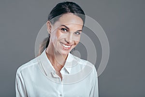 Happy young business woman ready to work posing against gray