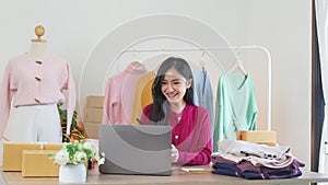 Happy young business woman using laptop taking online shop orders in home. Smiling fashion retail store owner