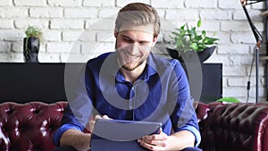Happy young businessman is analizing financial documents from home during self isolation on tablet.