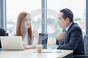 happy young businessman and businesswoman team working together with laptop computer on desk discussing information in office.boss