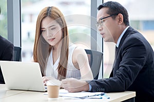 happy young businessman and businesswoman team working together with laptop computer on desk discussing information in office.boss