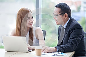 happy young businessman and businesswoman team working together with laptop computer on desk discussing information in office.boss