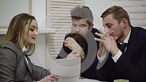 Happy young businessman and businesswoman team working together with paper docs on desk discussing information in office