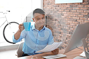 Happy young businessman with cup of coffee
