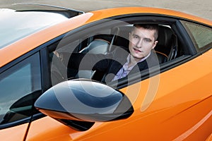 Happy young businessman driving luxury sport car