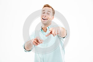 Happy young businessman laughing and pointing on you