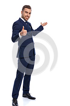 Happy young businessman making thumbs up gesture and smiling