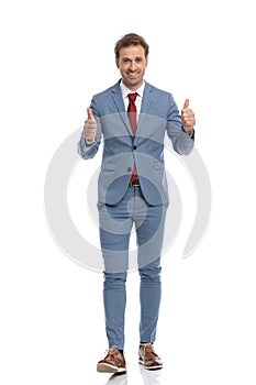 Happy young businessman making thumbs up gesture and smiling