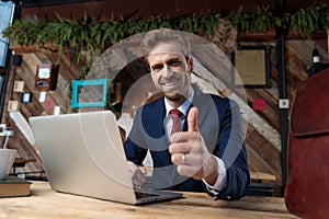 Happy young businessman making thumbs up sign