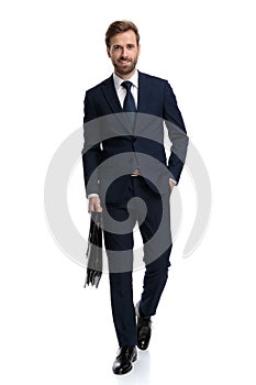 Happy young businessman in navy blue suit holding suitcase